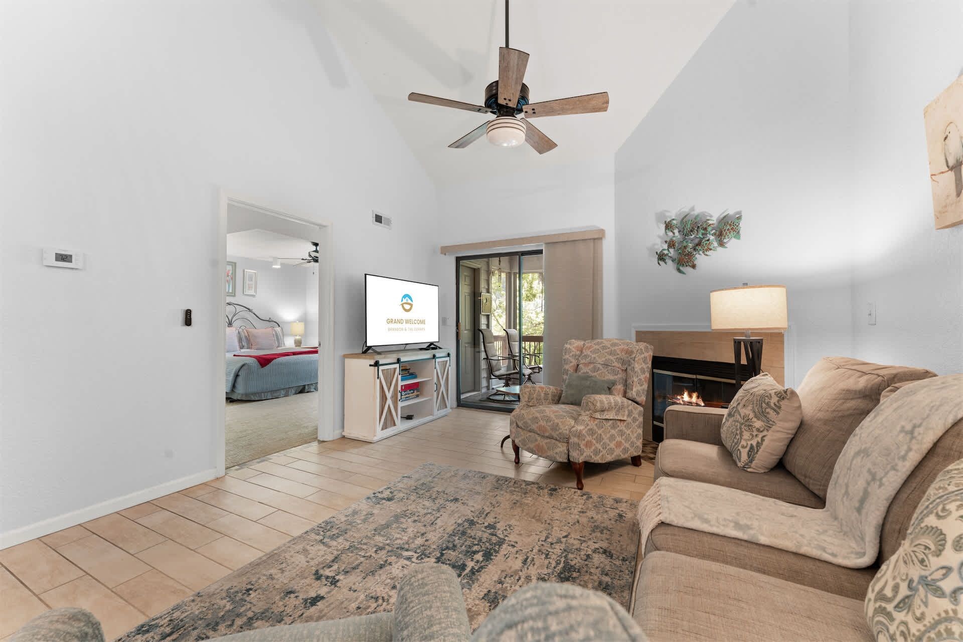 A spacious living room with a ceiling fan, a fireplace, a television, and a sofa.