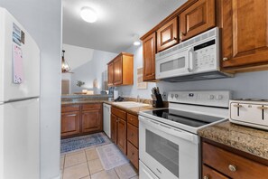 A kitchen with wooden cabinets, a microwave, a stove, and a refrigerator. - Serenity by the Lake - 3BR Home (Branson)