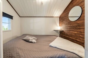 Ein Schlafzimmer mit Bett, Nachttisch, Lampe und Fenster.