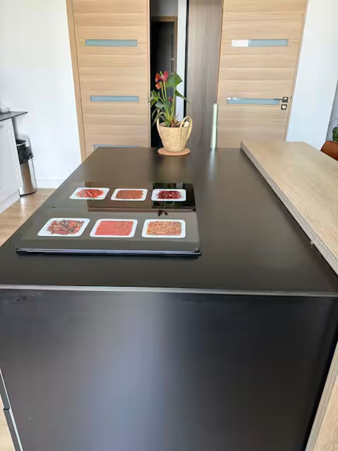 Een keuken met een zwart aanrechtblad, houten kastjes en een potplant.