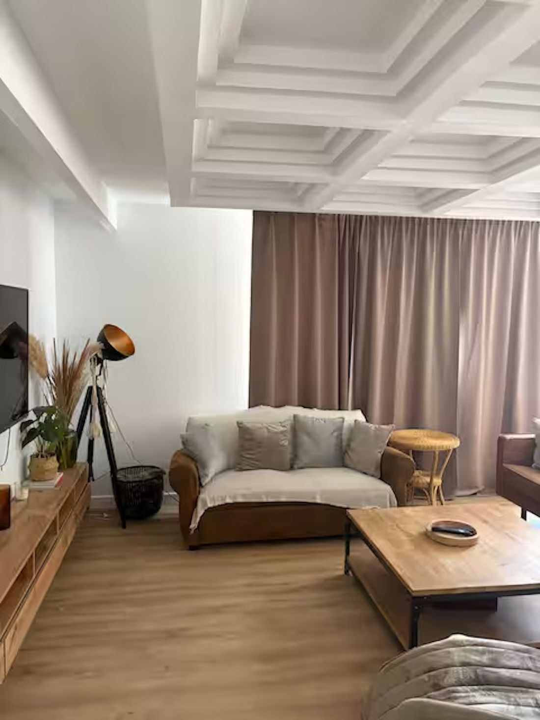 Una sala de estar con un sofá, una mesa de centro, un televisor y una lámpara.