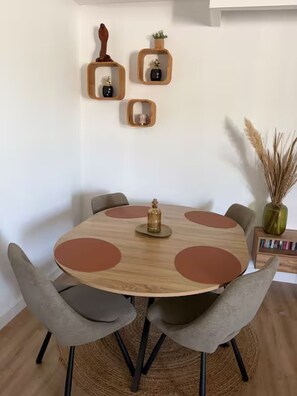 A round wooden table with a central decorative bottle, surrounded by six chairs.