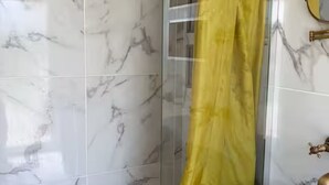 A bathroom with marble tiles, a shower enclosure, and a sink with a gold faucet. - Le Pignole · 2-bedroom apartment with AC and parking · Shared pool and garden · Sleeps 5 (Saint-Jory)