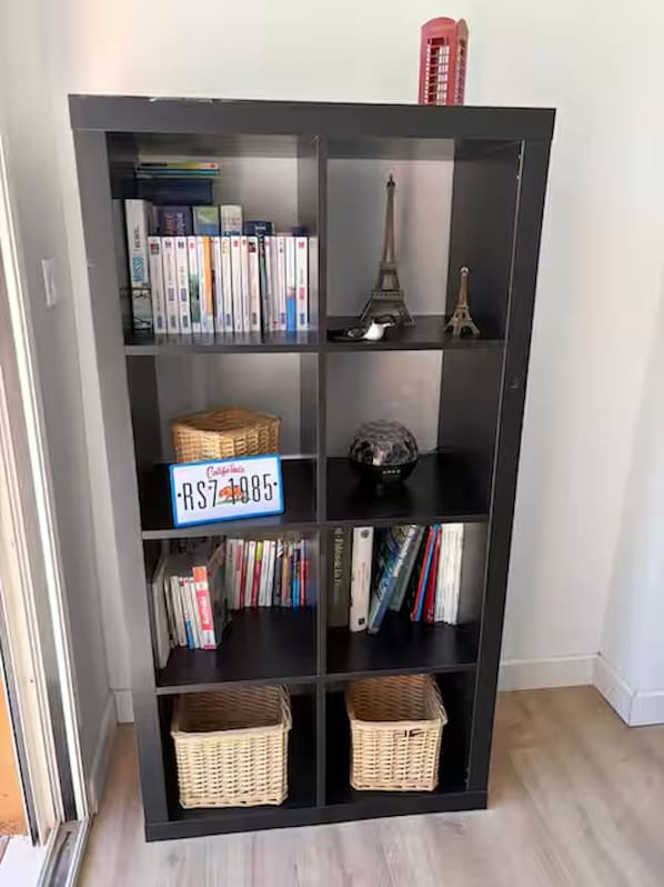 A bookshelf with multiple shelves, some containing books and others with decorative items like baskets and a small Eiffel Tower model.
