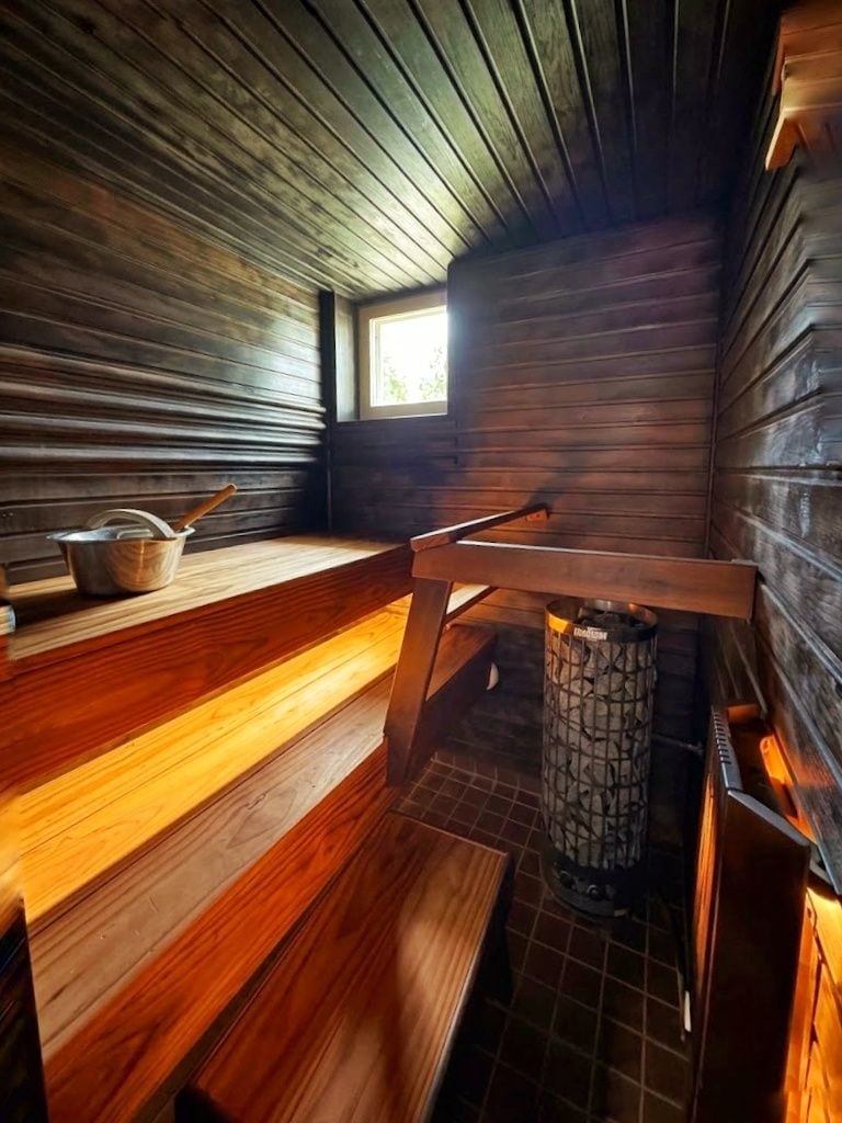 A sauna room with wooden benches and a central heating element.