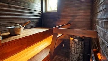 A sauna room with wooden benches and a central heating element.