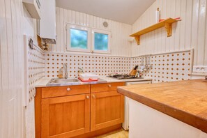 A kitchen with wooden cabinets, a sink, a window, and a wooden countertop.