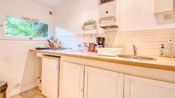 A kitchen with a window, a sink, a coffee maker, and cabinets.