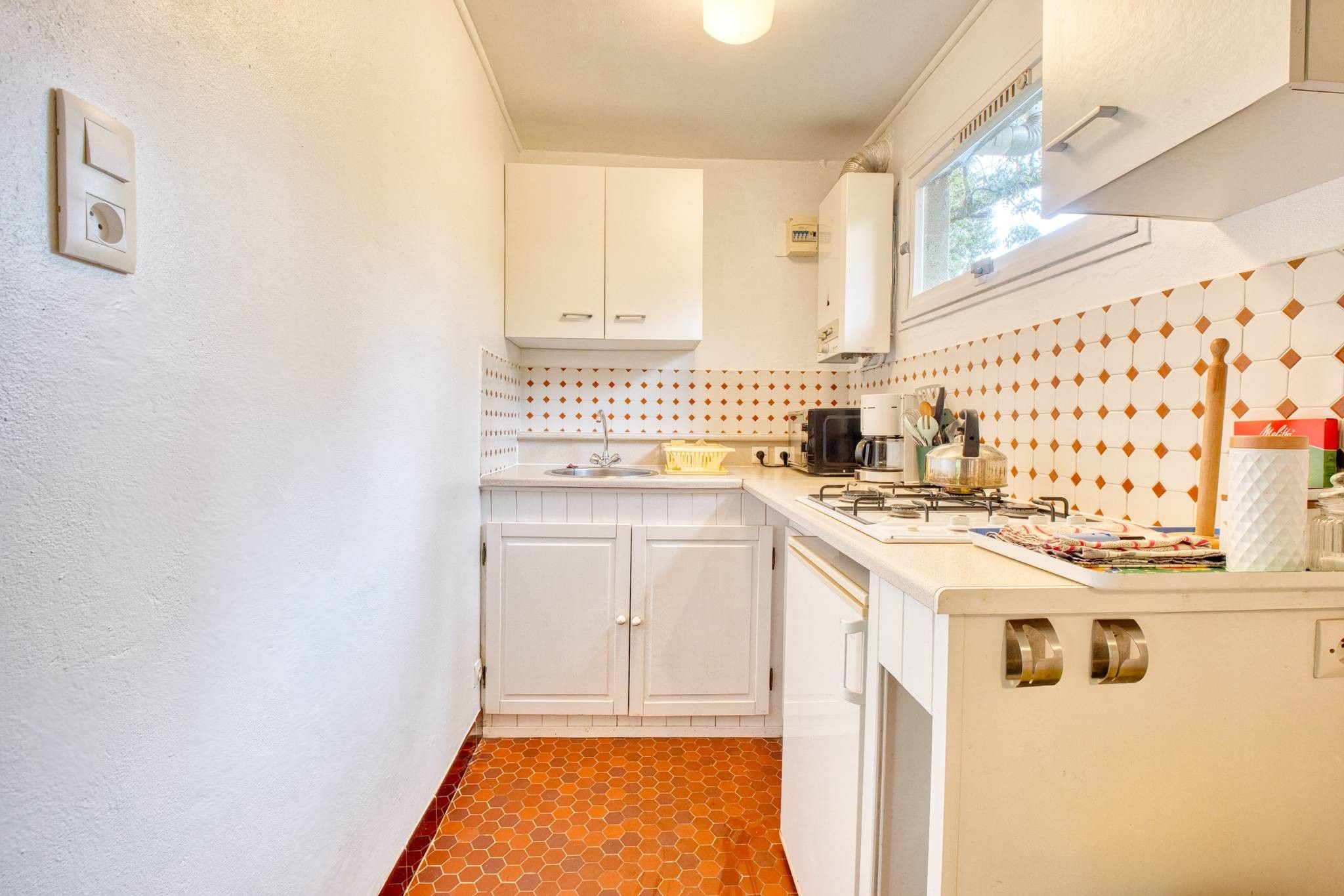 Une cuisine de taille réduite, avec des meubles blancs, un four à micro-ondes et une cuisinière à gaz.
