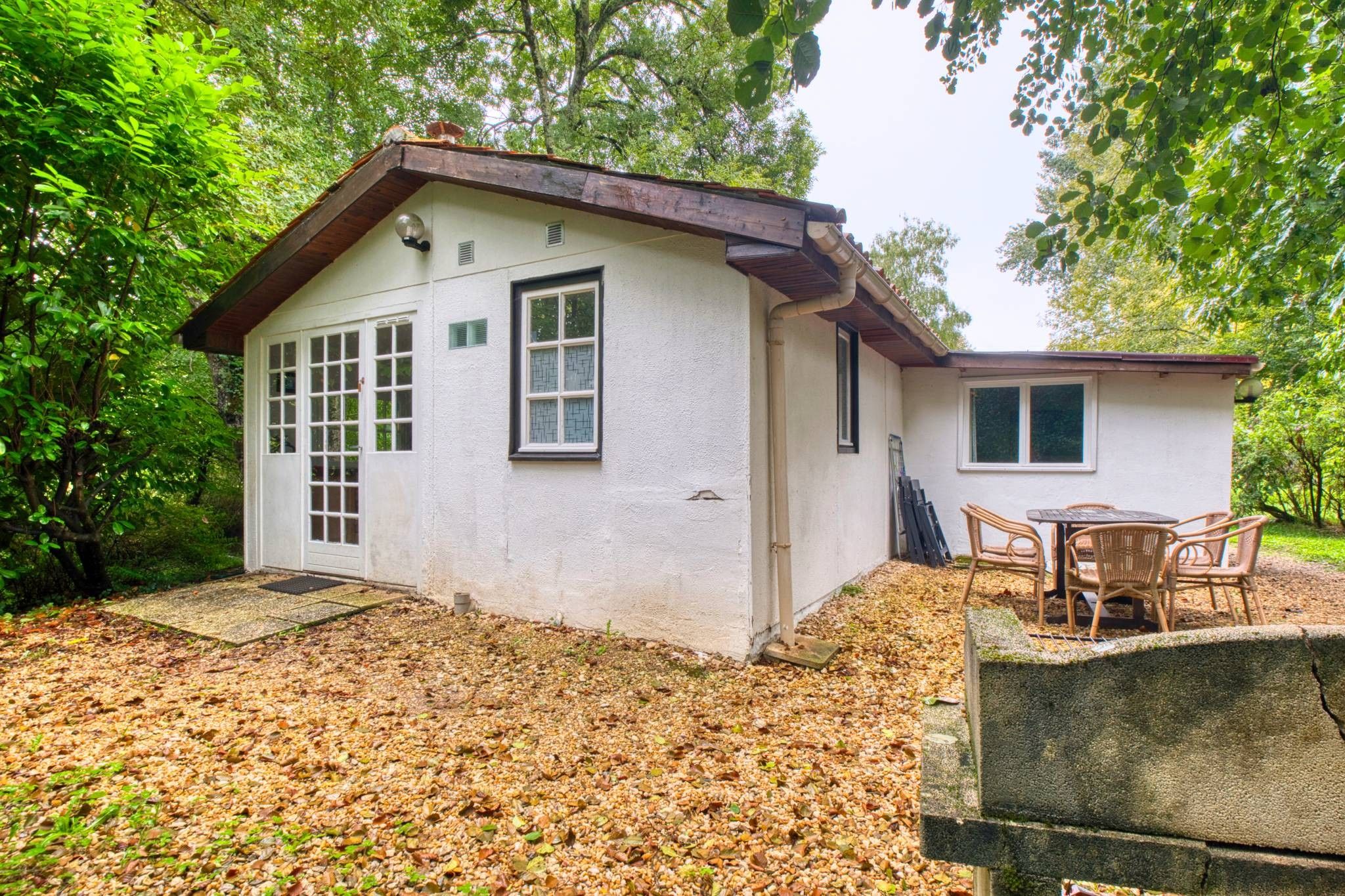 A small, single-story house with a porch and a table with chairs.