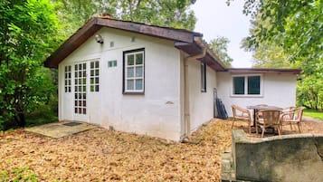 A small, single-story house with a porch and a table with chairs.