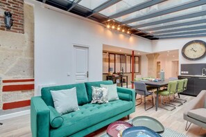 Ein stilvolles Wohnzimmer mit einem grünen Sofa, einem Esstisch und Stühlen.