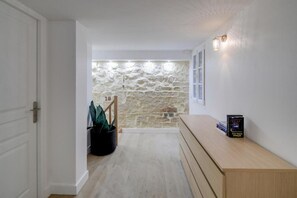 Ein Flur mit Steinwand, einer hölzernen Bank und einem Blumentopf.