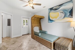 Ein Zimmer mit einem Korbmöbelbett, einer Tür, einem Gemälde und einem Deckenventilator.