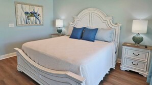 Ein Schlafzimmer mit einem großen Bett, zwei Nachttischen, einer Wandlampe und einem gerahmten Bild.