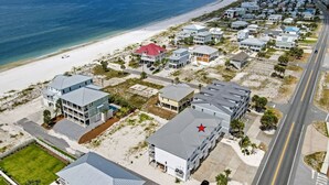 Eine Vogelperspektive auf ein Küstenwohngebiet mit Häusern, einem Strand und einer Straße.