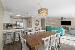 A modern kitchen with white cabinets, a wooden dining table, and bar stools. - NEW LISTING! A License to Chill, 4BD/3BA gulf front w/panoramic views, private p (Port St. Joe)