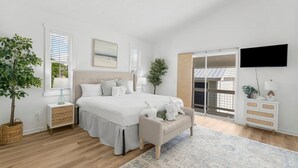 Ein Schlafzimmer mit Bett, Nachttischen, einem Fernseher und Blick ins Freie.
