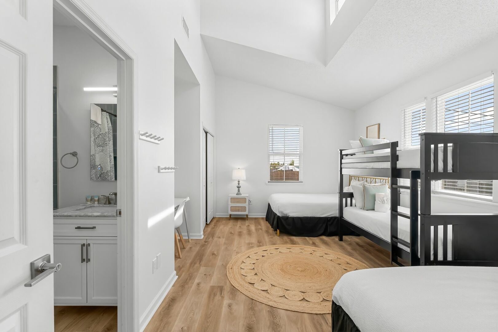 A modern bedroom with bunk beds, a bedside table, a lamp, and a view of the outside.