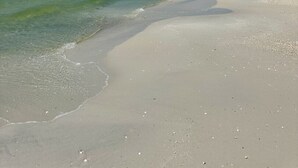 Ein Strand mit klarem Wasser und einem Sandufer.