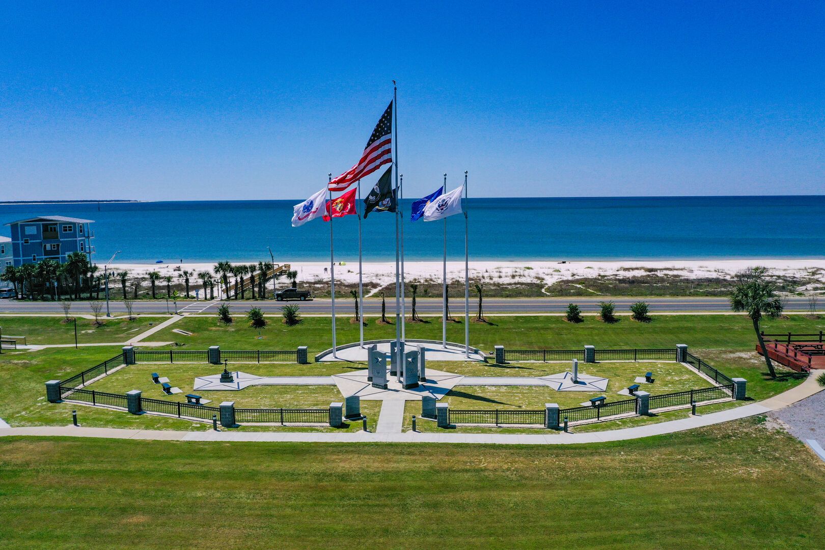 A flag display area with multiple flags, a circular walkway, and a view of the beach and ocean.