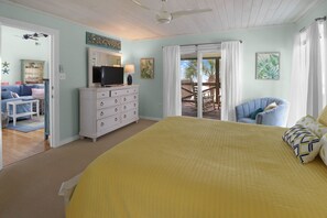 A bedroom with a large bed, a dresser, a television, and a view of an outdoor deck. - CABANA DEL SOL IS A 2BD/2BA GULF FRONT W/AMAZING VIEWS, 2 SCREEN PORCHES! (Port Saint Joe)