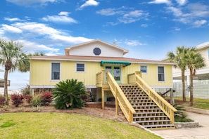A two-story house with a front porch, a staircase, and a small garden area. - CABANA DEL SOL IS A 2BD/2BA GULF FRONT W/AMAZING VIEWS, 2 SCREEN PORCHES! (Port Saint Joe)