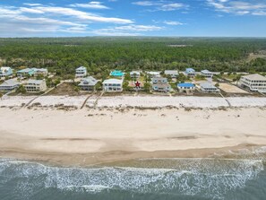 Une propriété située sur la côte, avec des villas en bord de mer, un symbole d’étoile indiquant un lieu remarquable, et une forêt dense en arrière-plan.
