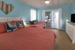 A bedroom with two beds, a TV, and a balcony with a view. - CABANA DEL SOL IS A 2BD/2BA GULF FRONT W/AMAZING VIEWS, 2 SCREEN PORCHES! (Port Saint Joe)
