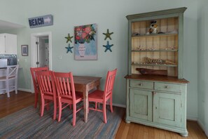A dining area with a wooden table and four chairs, a green cabinet with decorative items, and a wall sign indicating 'BEACH'. - CABANA DEL SOL IS A 2BD/2BA GULF FRONT W/AMAZING VIEWS, 2 SCREEN PORCHES! (Port Saint Joe)