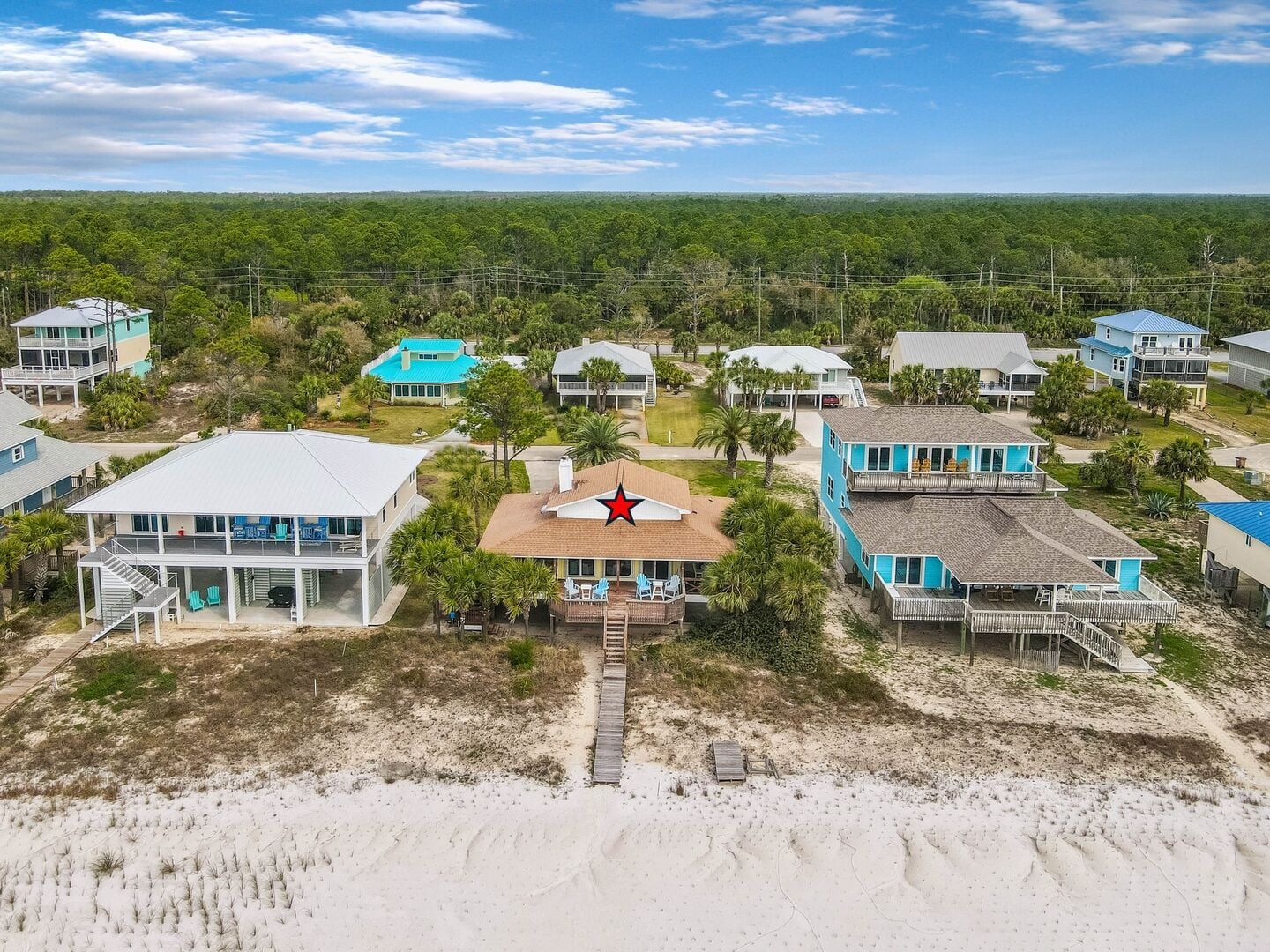 A coastal residential area with multiple houses, some with balconies, and a sandy beach in the foreground.