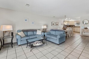 A living room with two sofas, a coffee table, and a dining area with chairs. - Cape it Simple -  OFFERS GULF VIEWS & STEPS TO THE BEACH! COMMUNITY POOLS! (Port Saint Joe)