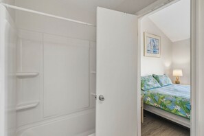 A bedroom with a bed, a nightstand, a lamp, and a framed picture on the wall. - Cape it Simple -  OFFERS GULF VIEWS & STEPS TO THE BEACH! COMMUNITY POOLS! (Port Saint Joe)