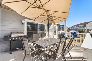 An outdoor patio with a grill, table, chairs, and a large umbrella. - Cape it Simple -  OFFERS GULF VIEWS & STEPS TO THE BEACH! COMMUNITY POOLS! (Port Saint Joe)