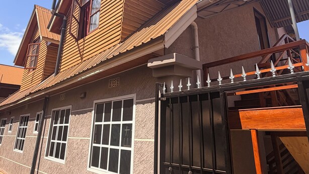 Un edificio a due piani con tetto spiovente, diverse finestre e un ingresso con cancello.