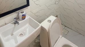 Un bagno con lavandino bianco, wc e doccetta a muro.