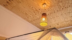 Un letto di legno con baldacchino, biancheria da letto bianca e una coperta rossa fantasia.