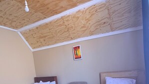 Una stanza con due letti, una sedia e una lampada a soffitto.