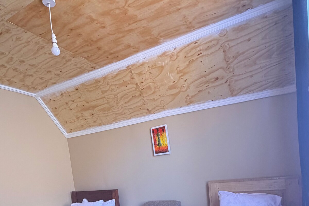 Una habitación con dos camas, una silla y una lámpara en el techo.