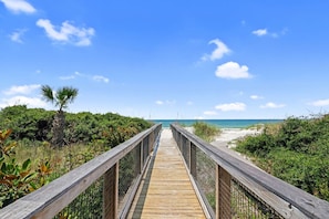 A wooden boardwalk leading to a beach with clear skies and vegetation on both sides. - Carpe Diem,  A Luxury Home With Amazing Gulf Views Views, Fire Pit, Pet-Friendly (Port Saint Joe)