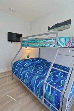 A bunk bed with a blue patterned bedspread, a wall-mounted television, and a decorative fish on the wall. - THIS DUPLEX IS PERFECT FOR LARGE FAMILIES/ MULIIPLE FAMILES! STEPS AWAY FROM THE (Mexico Beach)