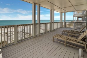 Um deck coberto ao ar livre com vista para a praia e o oceano.