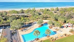 Ein Resort mit Schwimmbad, Liegestühlen und Blick auf Strand und Meer.