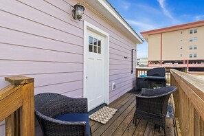A wooden deck with wicker chairs and a barbecue grill, adjacent to a building with a white door. - "Georgia Sand" is 600 steps to the beach! This 2BD/2BA adorable cottage sleeps 8 (Mexico Beach)