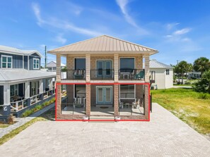 A two-story house with a balcony, a covered patio, and a driveway. - New Listing, Grand Coral II has gulf views & 100 steps to the beach! 2BD/1BA lux (Mexico Beach)