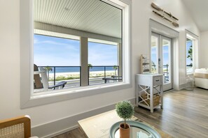 A room with a large window overlooking a beach, a small potted plant, and a white cabinet. - New Listing, Grand Coral III has gulf views & 100 steps to the beach! 2BD/1BA lu (Mexico Beach)