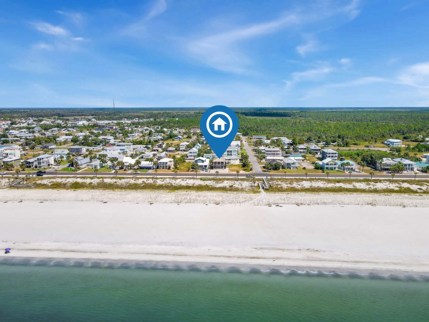 Une ville côtière avec une plage, des maisons et un ciel dégagé.