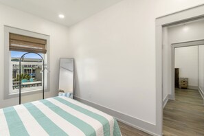 A bedroom with a bed, a window with a view, a mirror, and a door leading to another room. - New Listing, Grand Coral III has gulf views & 100 steps to the beach! 2BD/1BA lu (Mexico Beach)