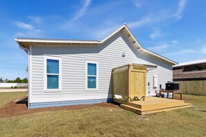 Een gelijkvloers huis met een veranda, twee ramen en een houten terras.
