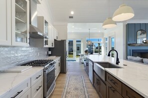 A modern kitchen with white cabinetry, a central island, and pendant lighting. - La Buena Vida is a 3BD/3BA, newly built home w/modern amenities, screened-in por (Mexico Beach)